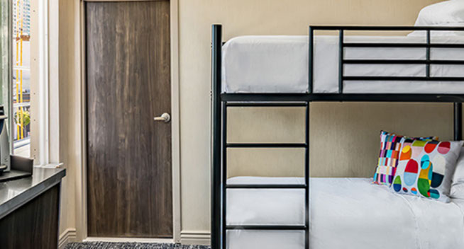 view showing bunk beds with colorful throw pillows, and large window for viewing city.