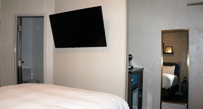 Full size bed, flat screen television with safe for valuables. Mirror at foot of bed. Bathroom entrance to the left of the bed.