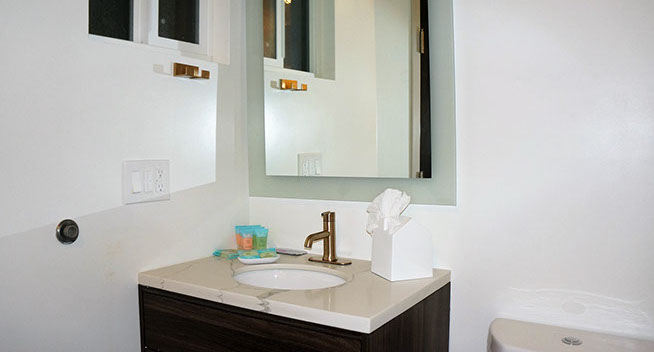 Photo showing your restroom facility. Single sink with brass fixtures, and medicine cabinet with mirror.