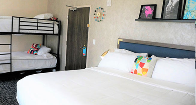 This room features a large king bed and a bunk bed for 2.  Colorful retro moderrn wall clock and photos above bed.