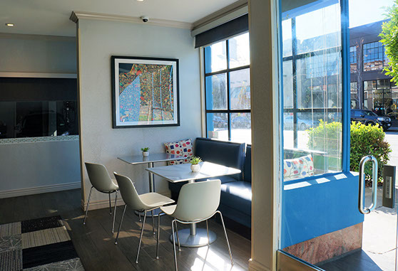 Photo of complimentary breakfast room in office area with table and chairs. Large windows for viewing city.